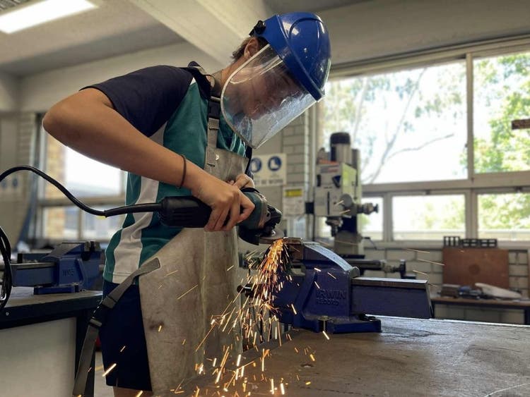 Student grinding metal in workshop